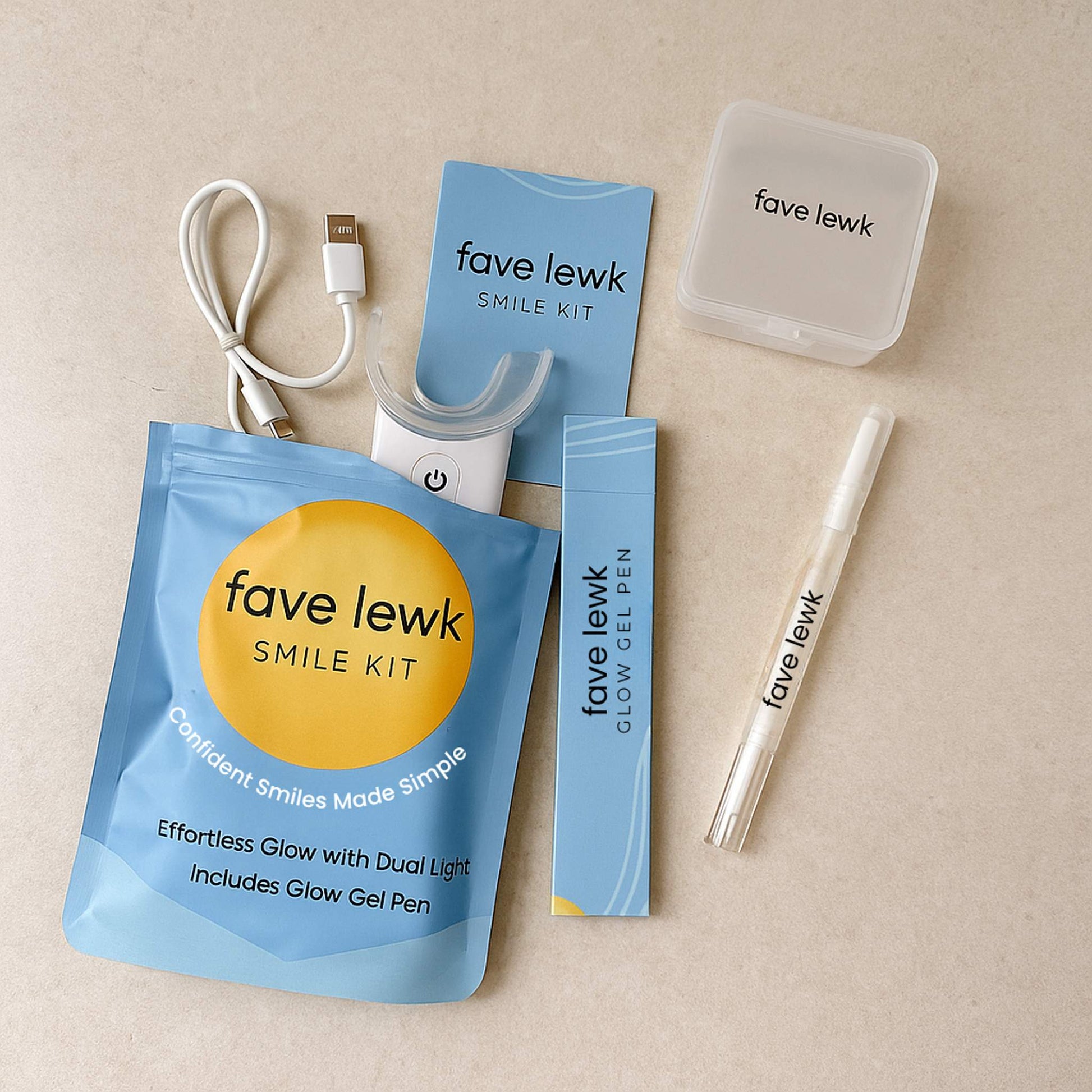 Flat lay of Fave Lewk Glow Bundle for at-home teeth whitening, featuring LED Smile Kit, Glow Gel Pen, charger, storage case, and refillable gel subscription